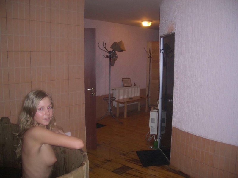 Голая блондинка лежит в деревянной ванне