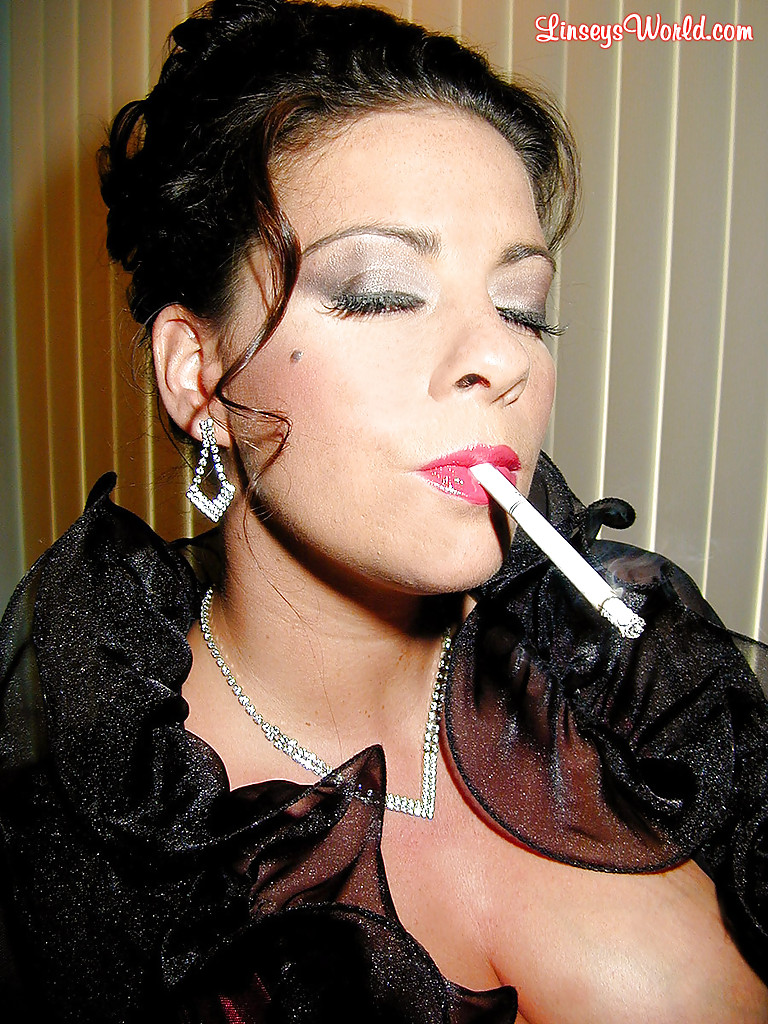 Пышногрудая мамка с сигаретой в руке позирует в сексуальном наряде