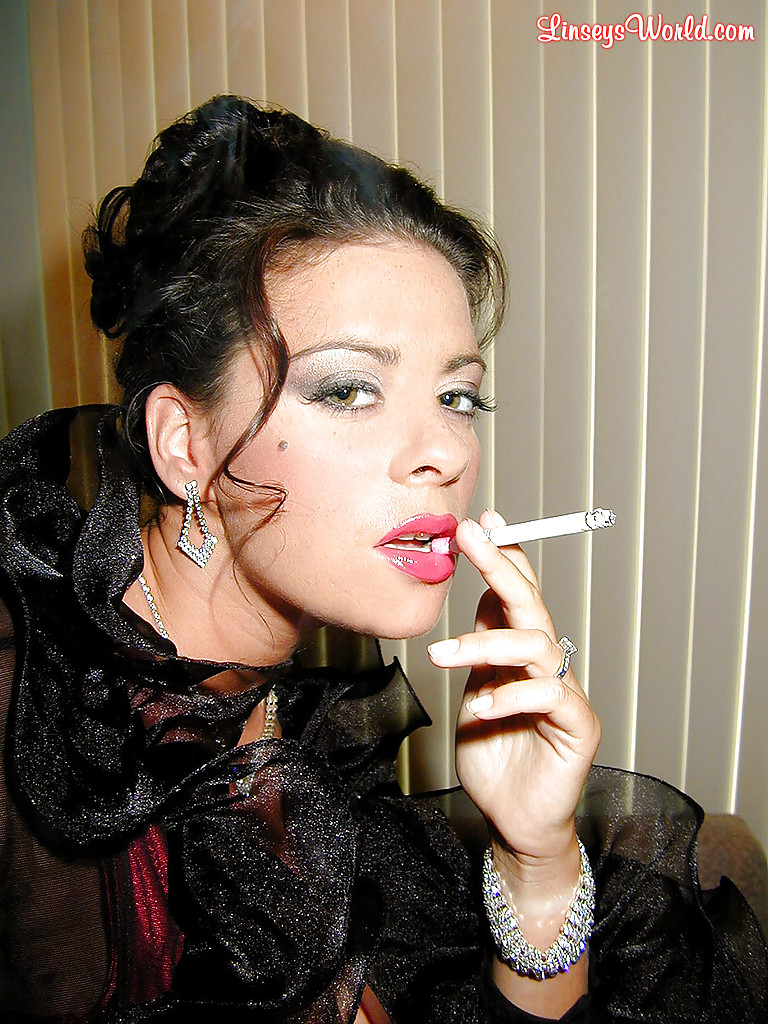 Пышногрудая мамка с сигаретой в руке позирует в сексуальном наряде